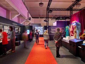 Several people in an exhibition hallway observing costumes and prints