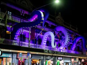 Four inflated octopus tentacle extend from the windows of a balcony above Brunswick Street.