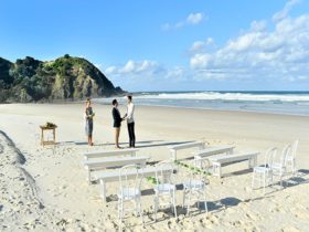 A couple saying their vows with the ocean in the background at Cosy Corner at Tallow Beach, Cape