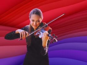 Grace Clifford is playing the violin, looking downwards and smiling
