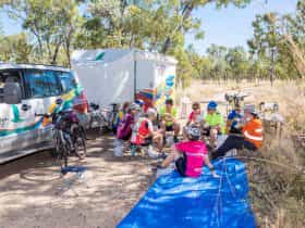 Guests sitting on stools next to Mulga Bicycle Tours trailer