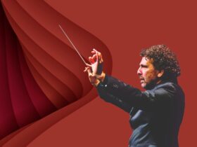 Side profile shot of Asher Fisch conducting with a serious look on his face