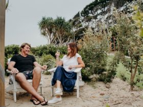 Two people sit in deck chairs holding glasses of wine