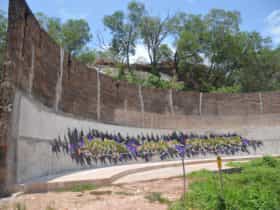 Oil tank wall with graffiti artwork to internal face of new concrete stabilising wall. Cracks in the wall have been repaired and can be seen in the image.