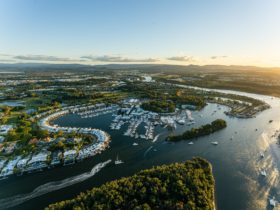 Ariel view of Sanctuary Cove, a harbour filled with white boats and surrounded by greenery.