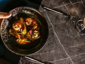 Top view from a dark plate with pan seared scallops being served on a table