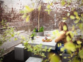 Photo shows a lady sitting at the table in the courtyard.