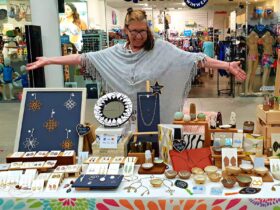 A stallholder smiling and displaying her wares at The Pier Markets