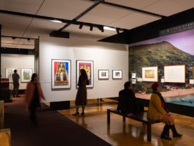Four people looking at items on the walls in a gallery. One person is walking through the gallery.