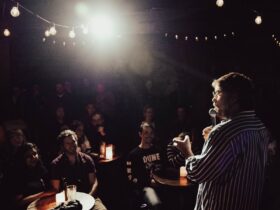 Comedian on stage, performing to a room full of people